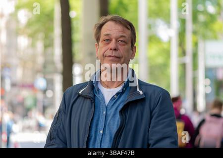 Un uomo maturo e sicuro guarda la fotocamera in un ambiente urbano Foto Stock
