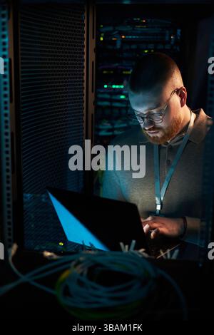 Lavorare nella sala server circondata da apparecchiature di rete Foto Stock