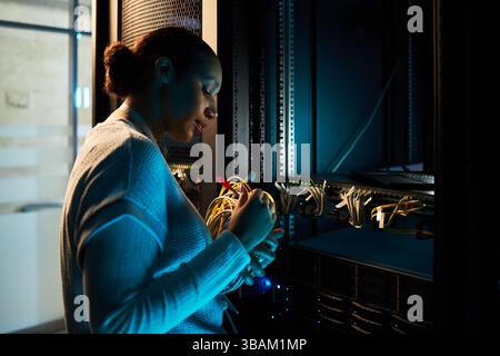 Donna asiatica che lavora nella sala server per data center Foto Stock