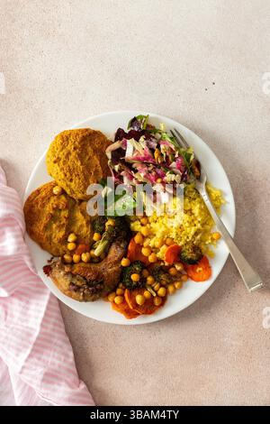 Una colazione ricca ed equilibrata con pancake di lenticchie e zucchine, miglio, collo di pollo al forno, patate dolci arrostite, broccoli, carote, ceci e un'insalata fresca con ravanello, germogli e noci Foto Stock