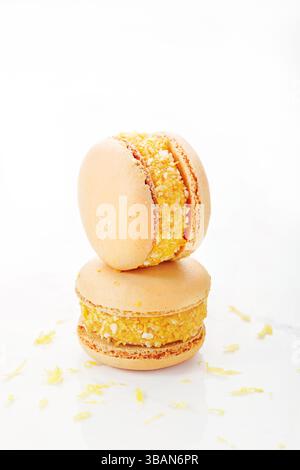 Primo piano di due macaron di limone impilati con ripieno di crema di cocco grattugiato su un tavolo Foto Stock