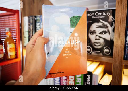 Leopoli, Ucraina - 4 maggio 2025: Amy Dempsley, Surrealismo. Una persona che espone un libro sul surrealismo, con librerie con vari titoli. Foto Stock