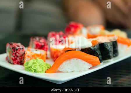 Assortimento di sushi e panini giapponesi preparati ad arte con salmone di prima qualità. Salutare presentazione di pesce con wasabi e zenzero. Foto Stock