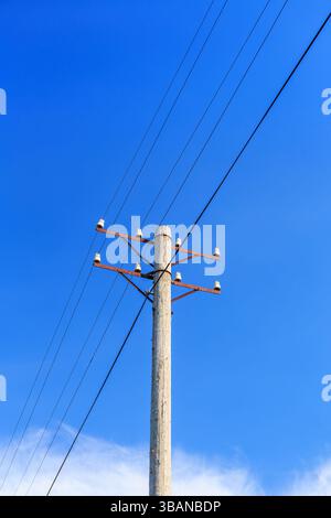 Asta del telefono con fili contro un cielo blu Foto Stock