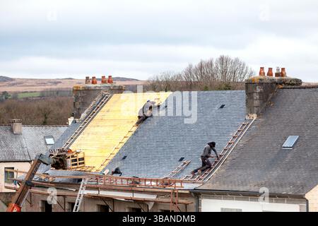 La Feuillée, Francia - 24 febbraio 2023: Sostituzione del tetto in ardesia di una piccola casa nel centro del paese. Foto Stock