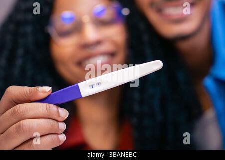 Coppia felice che tiene un test di gravidanza positivo e sorride con gioia ed eccitazione Foto Stock