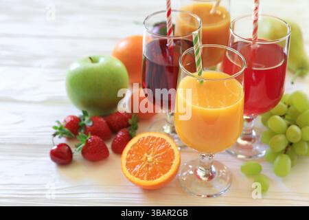 Una gamma colorata di succhi di frutta rinfrescanti offre bevande arancioni, rosse e verdi, oltre a frutta fresca su una superficie in legno, invitanti sapori e piaceri durante le calde giornate estive. Foto Stock
