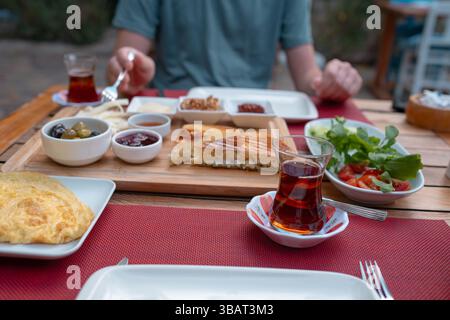 Colazione tradizionale turca con pane fresco, olive, formaggio, pomodori, cetrioli, e varietà di inceppamenti e spalmazioni. Godibile in un ambiente vivace Foto Stock