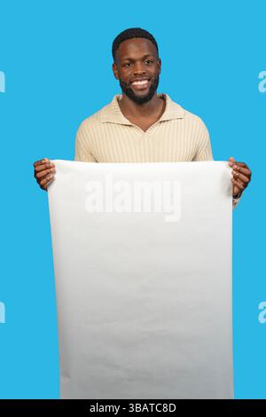 Ritratto in studio di un giovane uomo nero con uno striscione bianco verticale su uno sfondo blu vibrante Foto Stock