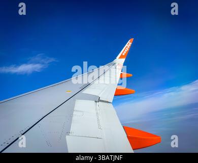 Sorvolando le nuvole a bordo di un Airbus A320 easyJet, questa splendida vista dell'ala cattura la bellezza del volo in una giornata limpida, con cieli blu profondi Foto Stock