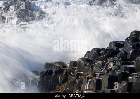 Primo piano delle onde che si infrangono sulle colonne basaltiche di Grand Causeway, Giant's Causeway, Antrim Coast, Irlanda del Nord Foto Stock