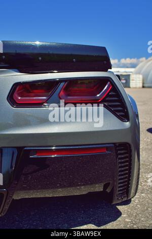 Primo piano posteriore di una moderna Chevrolet Corvette color argento con luci di posizione posteriori rosse e spoiler nero in una mostra di auto sotto il cielo blu. Foto Stock