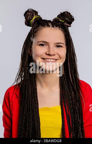 Giovane donna dai capelli intrecciati in un abito colorato che mette in risalto la sua vivace personalità Foto Stock