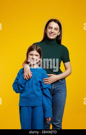 Ritratto verticale di bellissime sorelle sorridenti e che si abbracciano a vicenda posa per il ritratto di famiglia Foto Stock