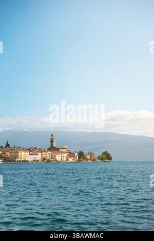 Vista panoramica della città costiera Salò sul lago di Garda con l'iconica torre della chiesa di fronte alle alpi sullo sfondo nelle giornate limpide Foto Stock
