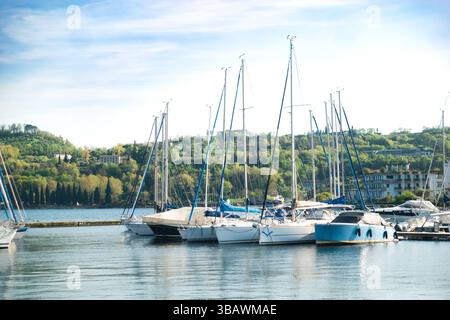 Piccolo porticciolo con barche a vela e motoscafi ormeggiati in estate dalla città di Salò sul Lago di Garda in Italia Foto Stock