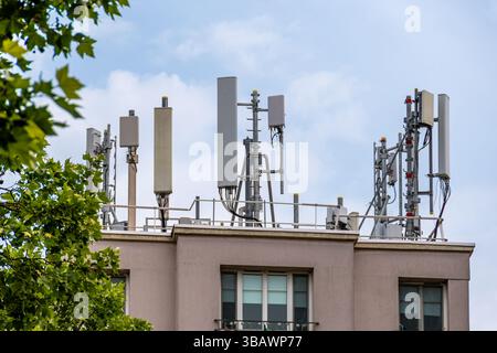 Antenne 4G e 5G appartenenti a un operatore di telecomunicazioni sul tetto di un edificio residenziale. Concetto di copertura della rete di telefonia mobile Foto Stock