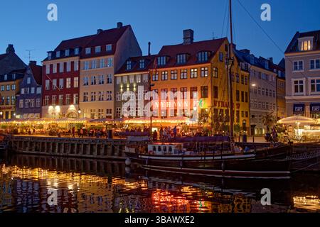 02.09.2024, Danimarca, Hovedstaden, Copenhagen - atmosfera serale sul canale Nyhavn nel quartiere di Frederiksstaden. La gente si siede fuori sotto il Foto Stock