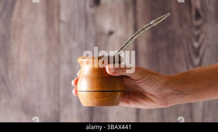 Una mano femminile che tiene un compagno di legno su fondo di legno. Foto Stock