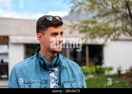 Un uomo giovane, felice e alla moda, sta camminando per la strada della città. Foto Stock