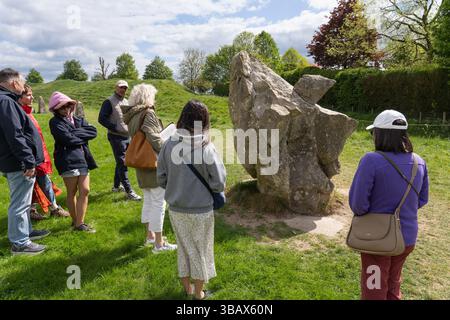 Il gruppo del tour ad Avebury riunito intorno alla pietra del fabbro n. 24 è un insieme di frammenti recuperati da una fucina da Alexander Keiller. REGNO UNITO Foto Stock