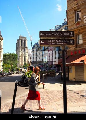 Notre-Dame in restauro vista da una strada di Parigi con una donna in gonna rossa, estate a Parigi Foto Stock