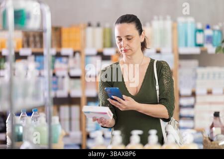 Donna di mezza età che esegue la scansione della confezione di pillole Foto Stock