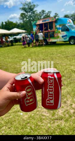 Mani che tengono in mano due bottiglie di vetro Coca-Cola in una giornata di sole con erba verde sullo sfondo. Rinfrescante concetto di drink estivo, all'aperto, stile di vita. Foto Stock