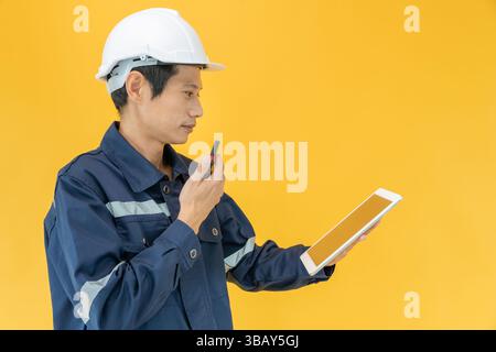Il tecnico indossa la sicurezza sul fondo colorato. ispezione dell'ispettore tramite tablet, responsabilità del progetto tecnico dell'ispezione. Servizio, industria, ingegneria civile Foto Stock