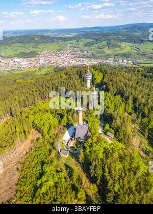 La vista aerea cattura la torre di osservazione di Svatobor immersa nel verde lussureggiante, con l'affascinante cittadina di Susice visibile nella valle sottostante, che mostra la bellezza del paesaggio cecoslovacco. Foto Stock