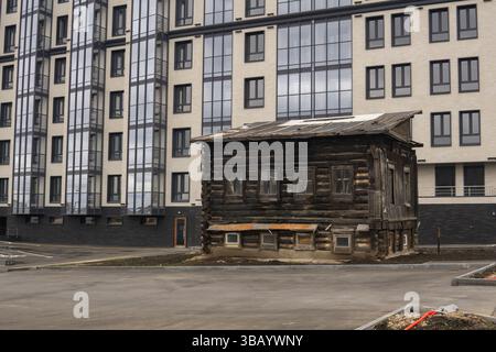 la vecchia casa in legno non è stata demolita per essere usata come sala di servizio durante la costruzione di un edificio moderno a più piani Foto Stock