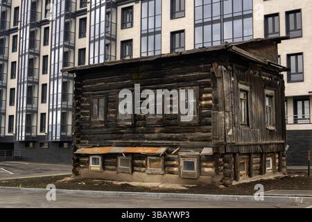 la vecchia casa in legno non è stata demolita per essere utilizzata come sala di servizio durante la costruzione di un edificio moderno a più piani Foto Stock