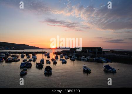 Lyme Regis, Dorset, Regno Unito. 14 maggio 2025. Meteo nel Regno Unito: Splendida alba sul porto presso la località balneare di Lyme Regis all'inizio di un'altra giornata calda e soleggiata. Crediti: Celia McMahon/Alamy Live News Foto Stock