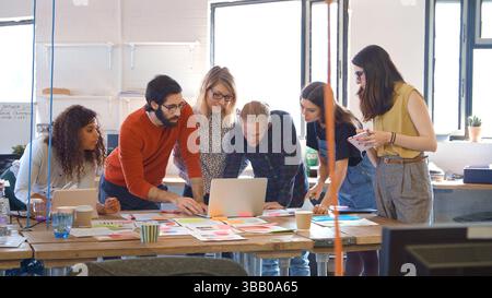 Riunione del team aziendale multiculturale in ufficio che esamina notebook e documenti Foto Stock