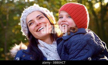 Primo piano di Mother Cuddling Daughter durante una passeggiata nella campagna autunnale con Lens Flare Foto Stock
