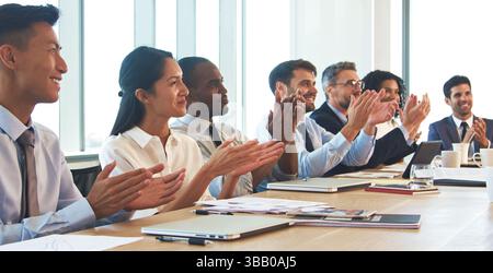 Presentazione di applauso del team aziendale intorno al tavolo in Modern Office Foto Stock