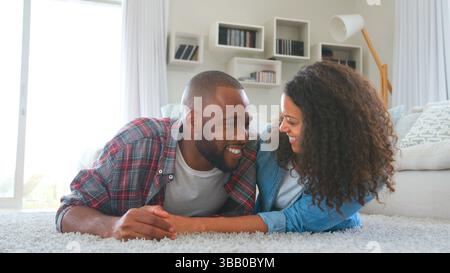 Coppia amorevole che giace su Rug in Lounge at Home Together Foto Stock