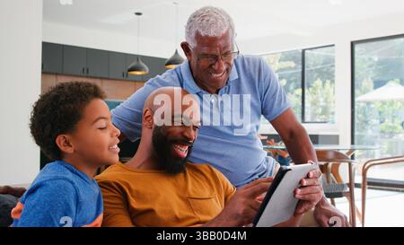 Famiglia afroamericana con Figlio seduto sul divano a casa Utilizzo di Digital Tablet Foto Stock