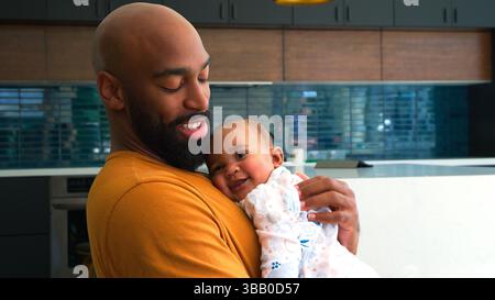Sorridente padre afroamericano Cuddling e giocare con Baby Daughter Indoors at Home Foto Stock