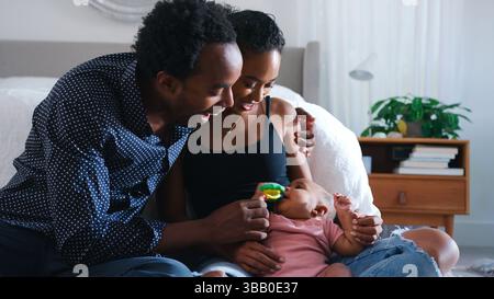 I genitori che amano giocare con la figlia del bambino che siede sul pavimento dentro Camera da letto Foto Stock