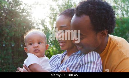 Genitori amorevoli che tengono la bambina a casa all'aperto nel giardino Foto Stock