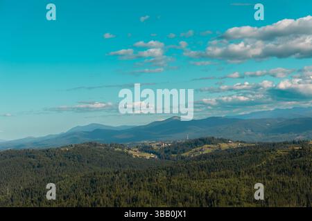 Vista panoramica di una lussureggiante catena montuosa verde sotto un cielo blu. Una vista panoramica mozzafiato di una lussureggiante catena montuosa verde che si estende sotto un luminoso Foto Stock