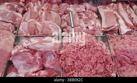 Assortimento di carne fresca in esposizione. Primo piano di vari tagli di carne cruda fresca, tra cui costolette, carne macinata e pezzi, esposti in un macellaio Foto Stock