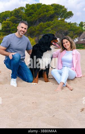 Ritratto caucasico di coppia con il cane in vacanza al mare sorridente alla macchina fotografica Foto Stock
