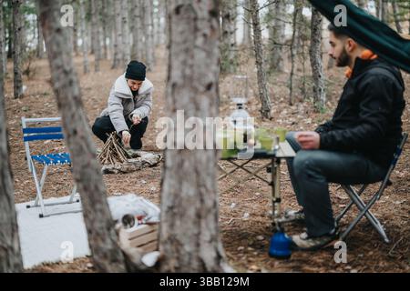Riscaldati accanto al falò mentre ti godi un meditato picnic invernale nella foresta panoramica Foto Stock