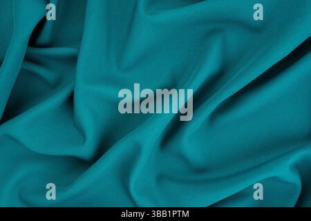 Splendido sfondo in raso di seta blu scuro e verde. Pieghe morbide su un tessuto lucido. Sfondo elegante con spazio di copia per il design. Foto Stock