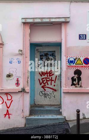 Votate a sinistra! Testo sulla porta della casa rosa al 31 di Rue Germain Pilon nel quartiere Montmartre di Parigi, Francia Foto Stock