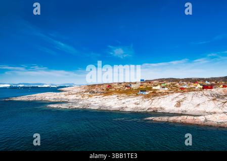 Il tranquillo villaggio di pescatori di Rodney, o Oqaatsut, in Groenlandia presenta case vibranti annidate contro rocce aspre, con acque cristalline Foto Stock
