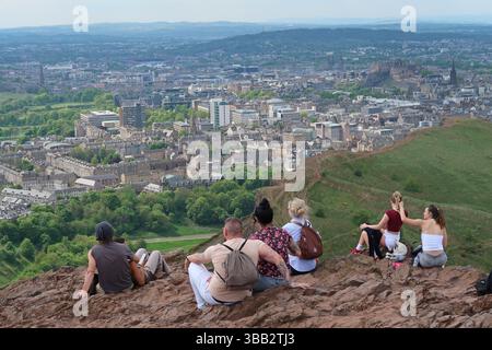 Arthur's Seat, Edimburgo, Scozia. I giovani ammirano la vista sulla città dal famoso monumento in un giorno di sole primaverili. Foto Stock
