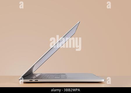 Vista laterale del notebook aperto su sfondo beige Foto Stock
